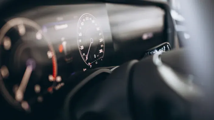Detalle del interior de un coche moderno con cuadro de instrumentos digital y volante que representa tecnología y control de la conducción