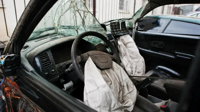 Interior de coche destruido con airbags desplegados tras accidente.
