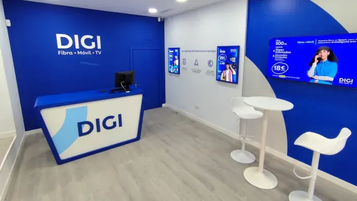 Grupo de cuatro trabajadores sonrientes posando sobre fondo azul corporativo de DIGI.