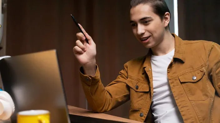 Autónomo joven señalando pantalla de portátil en videollamada de trabajo.