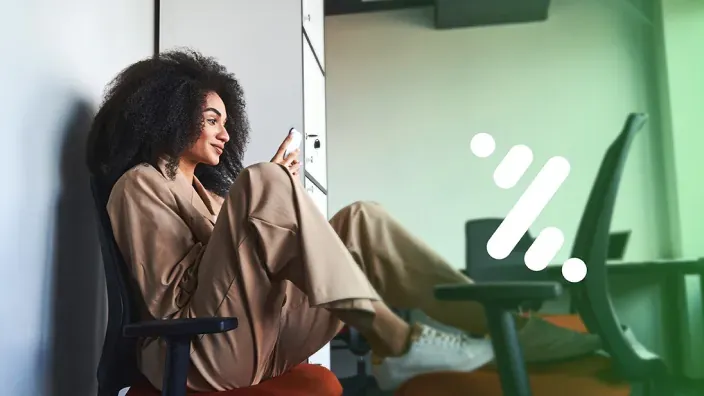 Mujer joven sentada usando su teléfono móvil en una imagen corporativa de Unicaja.