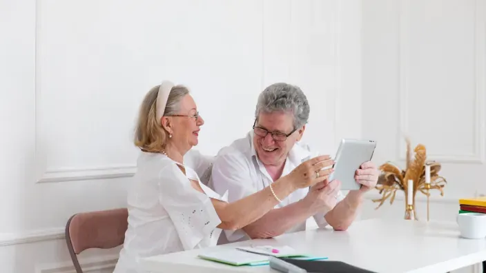 Pareja de mayores usando una tablet para gestionar sus ahorros y banca digital desde casa.