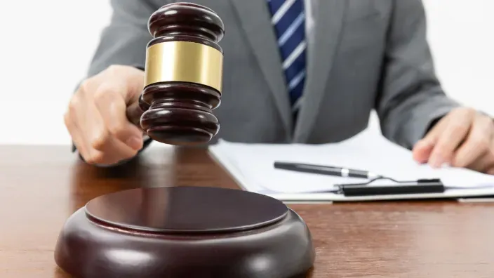 Juez con traje y corbata a punto de golpear con el mazo para dictar sentencia. Símbolo de ley, justicia y veredicto.