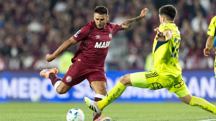 Jugador de Lanús intentando controlar el balón ante un rival durante un partido.