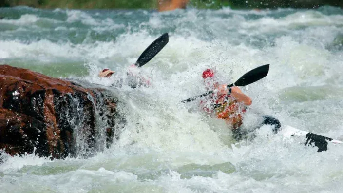 Piragüistas en una situación de riesgo en un río de aguas bravas. La importancia de un seguro de accidentes y viaje.