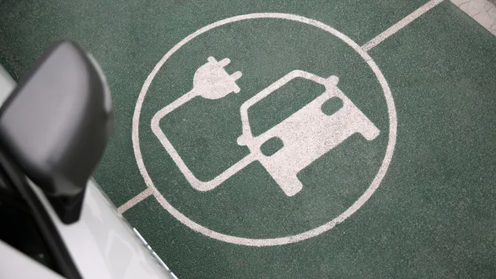 Coche eléctrico aparcado en una plaza de recarga con el símbolo de vehículo eléctrico pintado en el suelo.