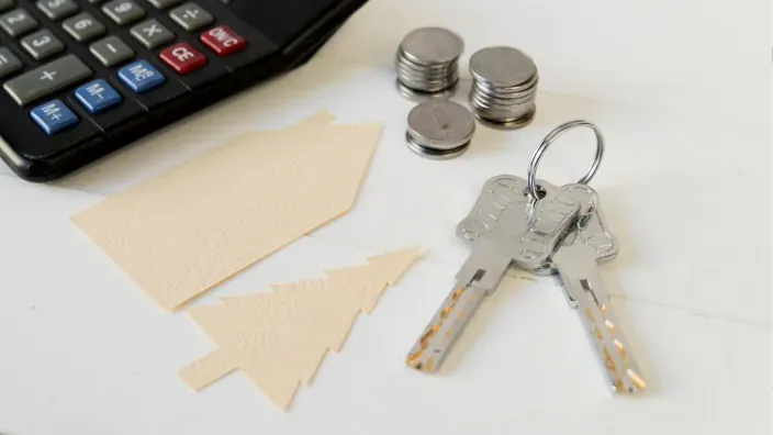 Llaves de una vivienda junto a monedas y calculadora, símbolo de la conversión del patrimonio inmobiliario en liquidez.