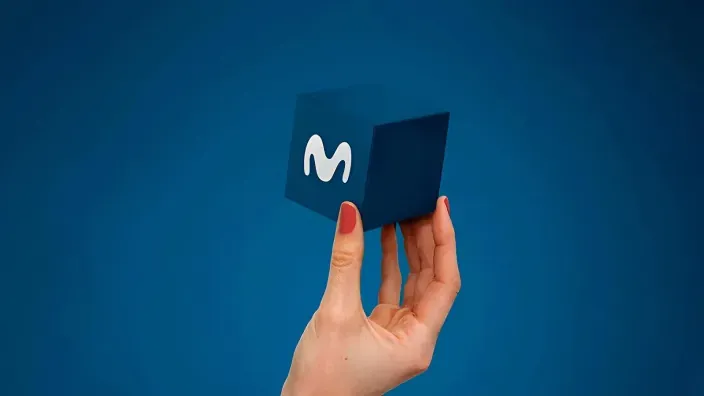 Mano sosteniendo un cubo azul con el logo de Movistar. Descubre la oferta integral de servicios de fibra, móvil y televisión.