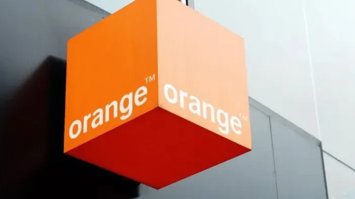 Cubo naranja con el logotipo de Orange colgado en la fachada de un edificio.