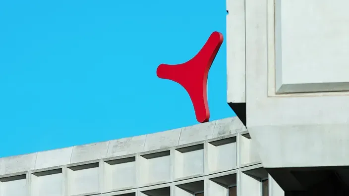 Primer plano del icónico logo rojo de Grupo Catalana Occidente en la azotea de su sede.