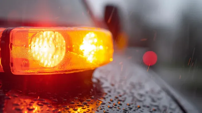 Luz de emergencia encendida en un coche averiado bajo la lluvia.