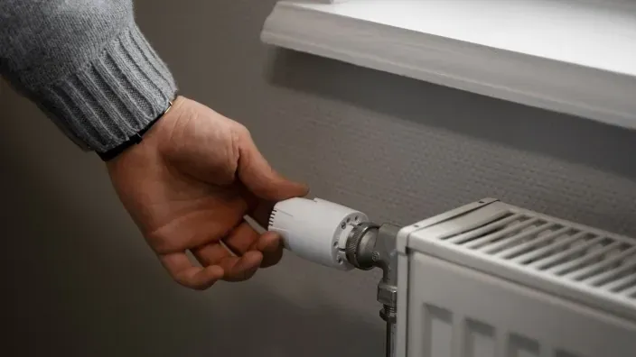 Mano ajustando la válvula de un radiador de calefacción.
