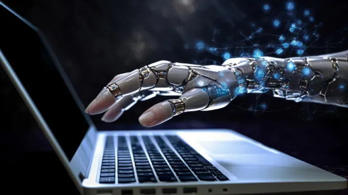 Mano robótica tecleando en un ordenador portátil para representar la automatización e inteligencia artificial.