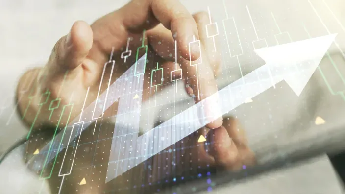 Mano tocando una tablet con un gráfico financiero ascendente superpuesto