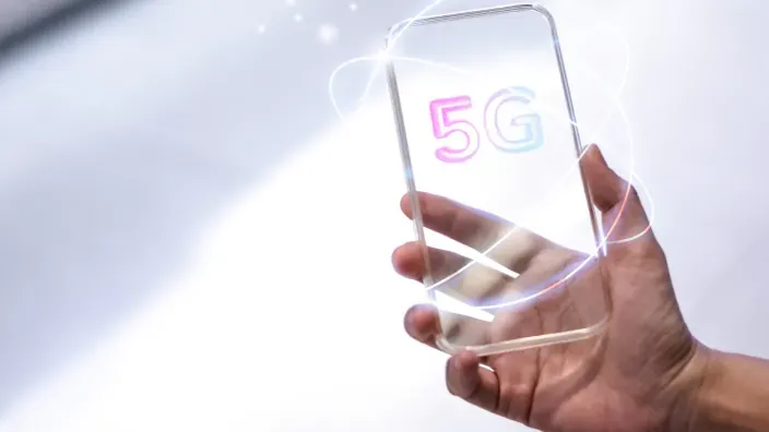 Mano sosteniendo un móvil transparente con el texto 5G iluminado.