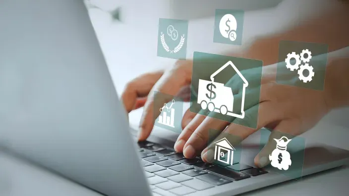 Manos escribiendo en un portátil con iconos digitales relacionados con finanzas y vivienda