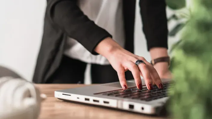 Manos escribiendo en un portátil sobre una mesa