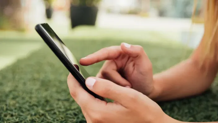 Primer plano de manos utilizando un smartphone al aire libre.