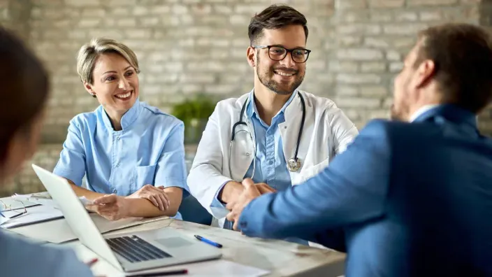 Médico sonriente dando buenas noticias a un paciente durante una consulta médica.