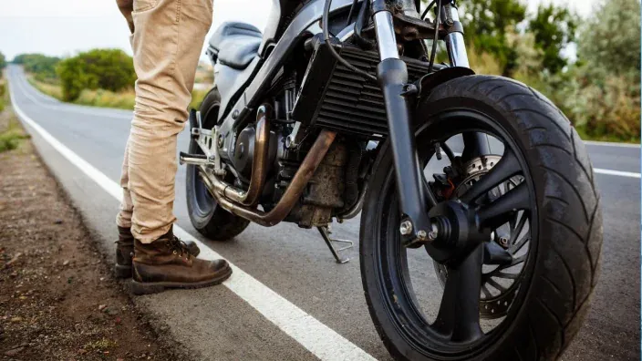 Motociclista detenido junto a su moto en una carretera rural