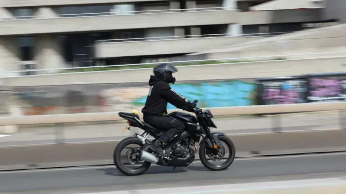 Conductor de moto circulando por una avenida urbana con casco negro