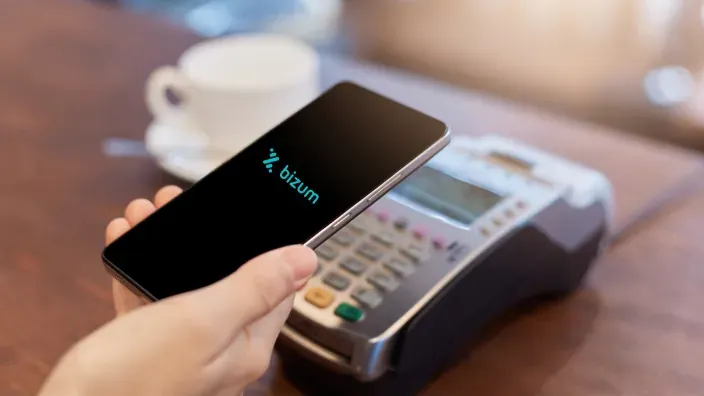 Cliente realizando pago con Bizum a través del móvil en un terminal datáfono.