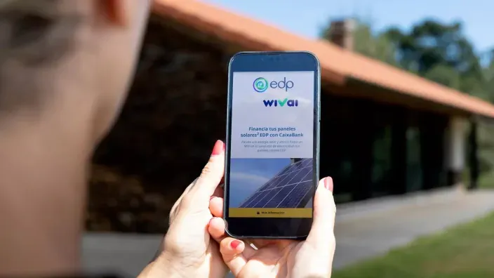 Persona sujetando un móvil con una publicidad de EDP para financiar paneles solares.