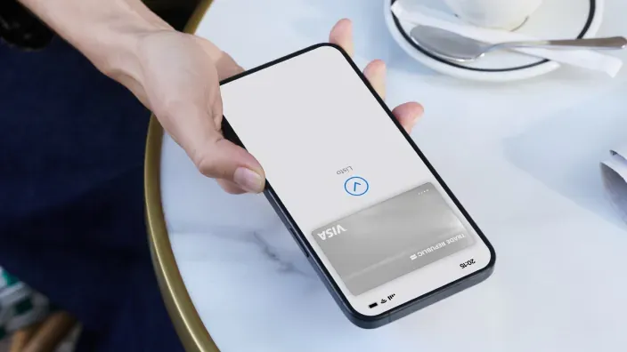 Mano sujetando un móvil con una tarjeta Visa de Trade Republic mostrada en una billetera digital