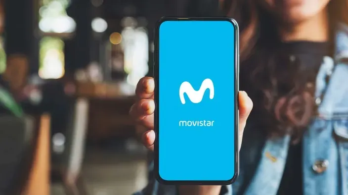Persona sosteniendo un móvil con el logo de Movistar en pantalla, representando servicios de telefonía y tarifas móviles de la compañía.