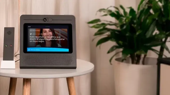 El dispositivo Movistar Home en un salón, mostrando noticias de actualidad en su pantalla. Altavoz inteligente para el hogar conectado