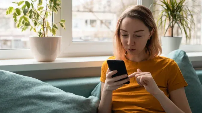 Clienta usando la app de su banco en el móvil para gestionar sus finanzas o revisar una alerta de seguridad.