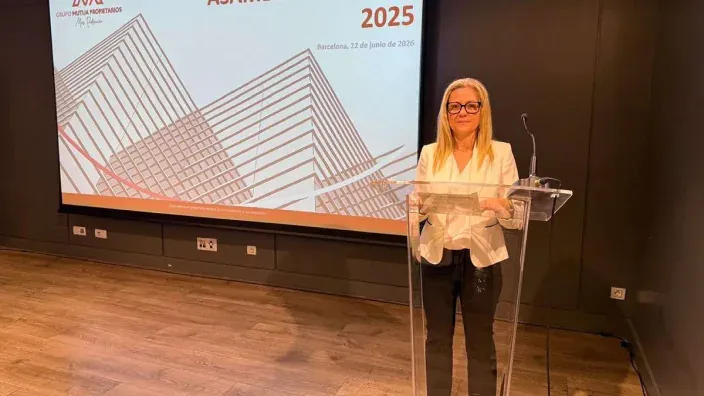 La presidenta de Grupo Mutua Propietarios en un atril durante una presentación corporativa con una pantalla al fondo