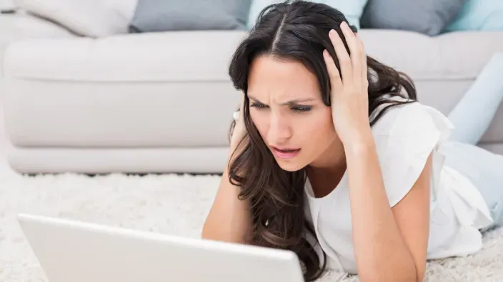 Mujer preocupada frente a su portátil para representar problemas de conexión a internet.