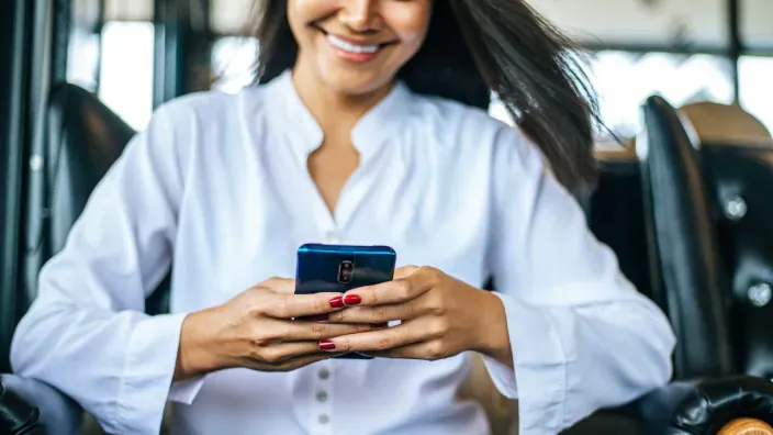 Mujer sonriente chateando con smartphone en transporte público o taxi.