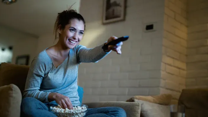 Mujer viendo la televisión y disfrutando de una película en casa