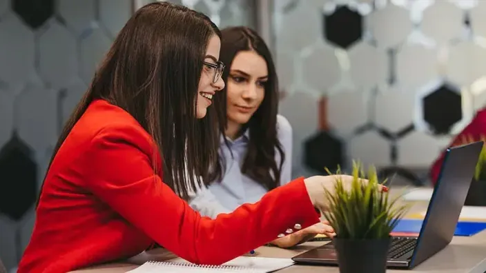 Mujeres profesionales colaborando frente a un portátil para representar el liderazgo femenino y el trabajo en equipo.