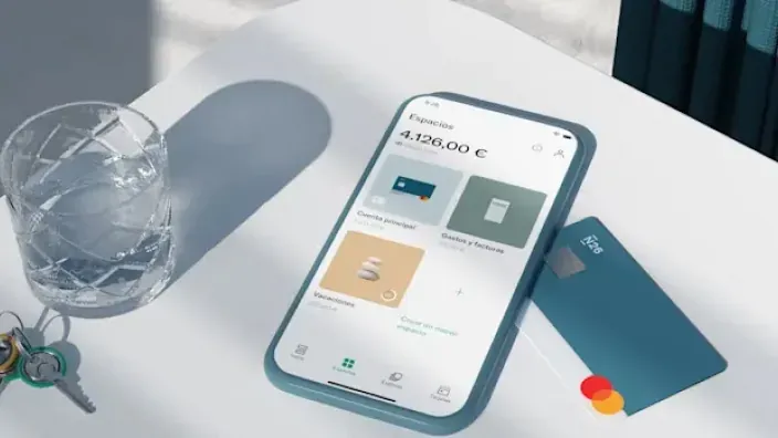 App de N26 en un smartphone mostrando saldo en Espacios junto a la tarjeta bancaria para ahorro y banca digital.