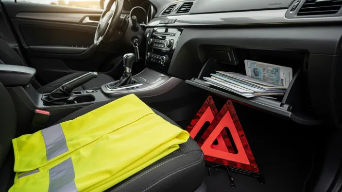 Interior de un coche con el kit de seguridad: chaleco reflectante, triángulos de emergencia y la documentación en la guantera