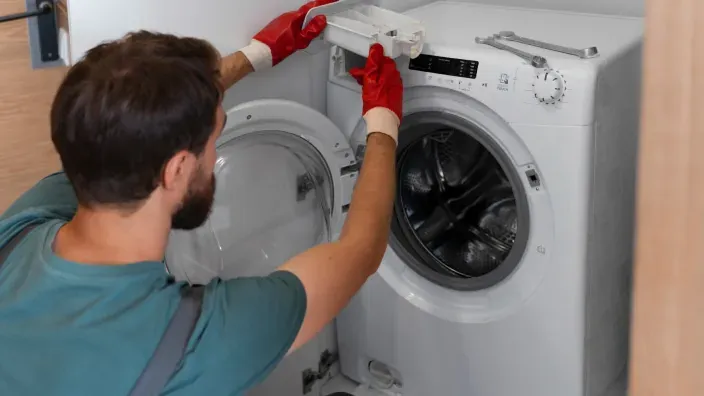 Técnico revisando una lavadora en el domicilio de un cliente