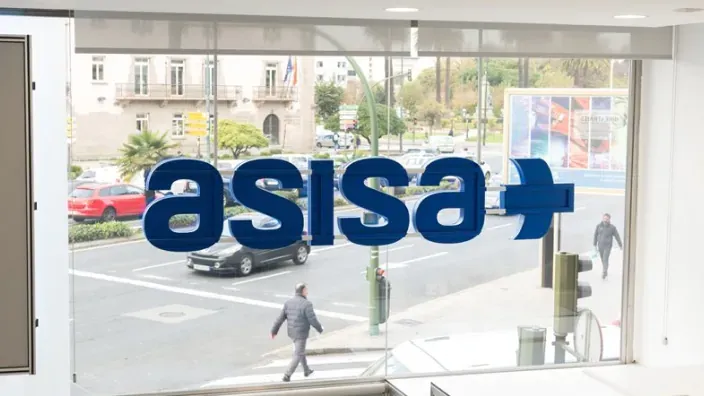 Oficina de Asisa desde dentro, con el logo en el medio y personas de fondo andando por la calle.
