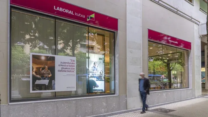 Fachada de una oficina de LABORAL Kutxa en una calle comercial con escaparates y señalización corporativa.