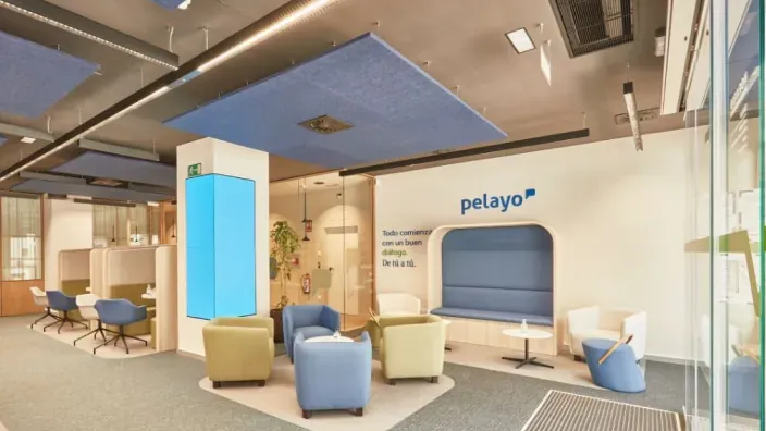 Interior de oficina de Pelayo con zona de atención al cliente y área de espera con sillones.