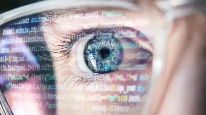 Primer plano de un ojo con reflejos de código y datos superpuestos