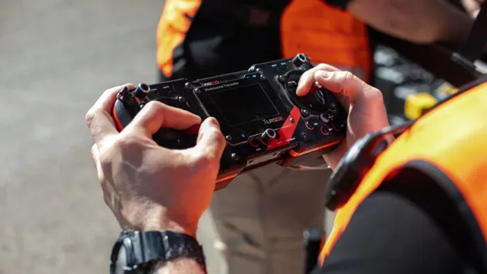 Operario sosteniendo un mando de control de dron con chaleco reflectante