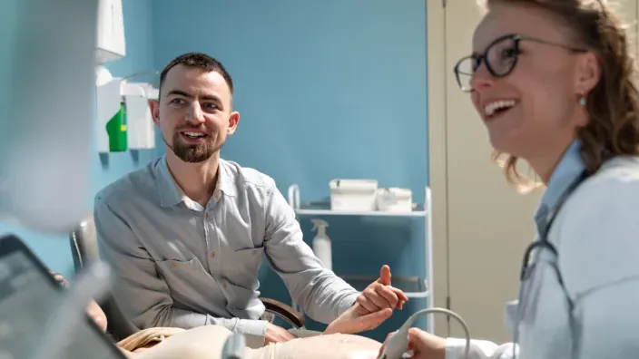 Paciente sonriendo durante una consulta médica acompañado por profesionales sanitarios.