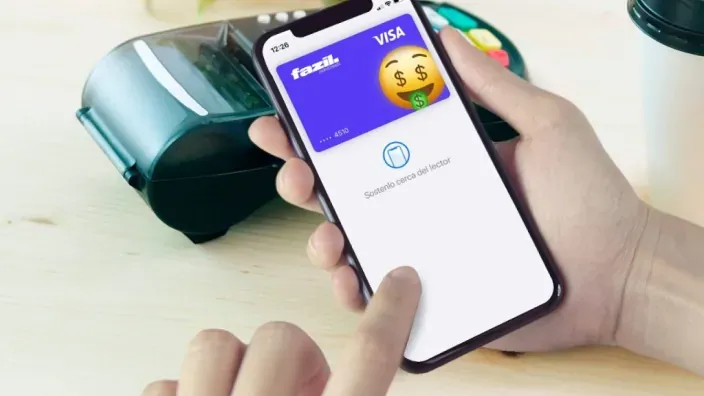 Mano sosteniendo un móvil con una tarjeta digital junto a un datáfono