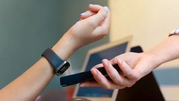 Cliente realizando un pago contactless con su smartwatch en un datáfono.