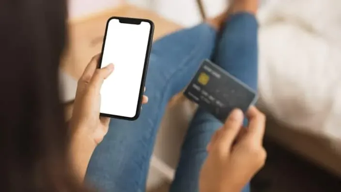 Persona realizando un pago con tarjeta bancaria desde el móvil, compra online segura