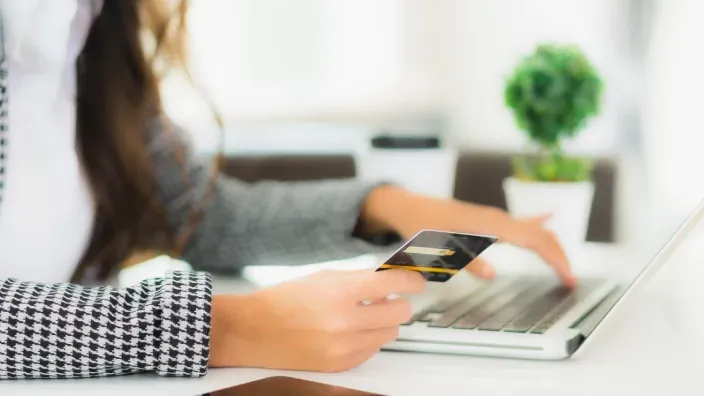 Mujer realizando un pago online con tarjeta de crédito mientras utiliza un ordenador portátil.