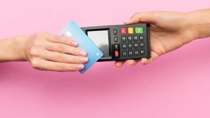 Persona realizando un pago sin contacto con tarjeta bancaria sobre un terminal de punto de venta.